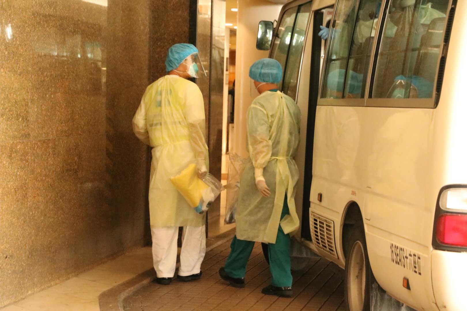 衞生署安排3輛中型旅遊巴，接載酒店員工去往檢疫中心。（點新聞記者攝）