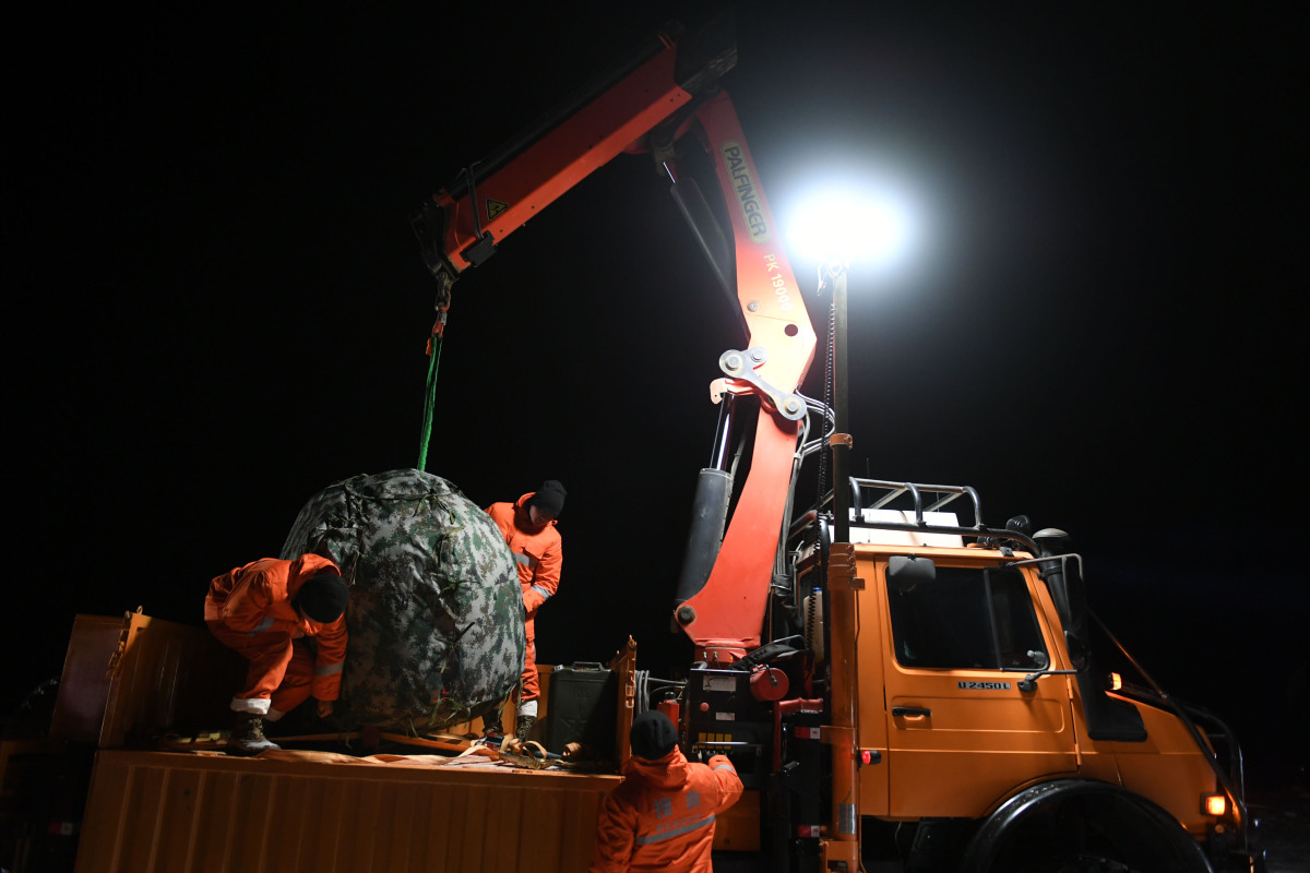 工作人員將返回器吊運至裝載車輛。（新華社）