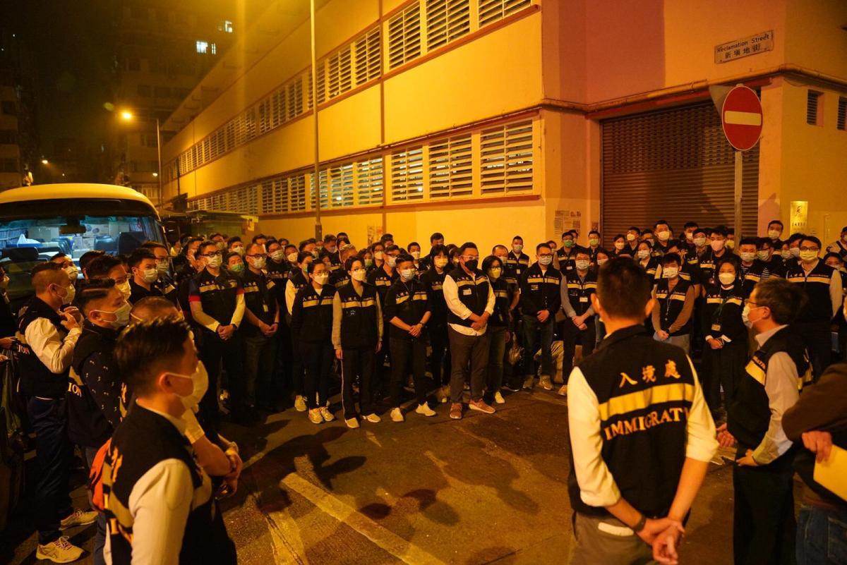 油麻地區疫情持續升温，政府首度實施圍封，劃定佐敦一帶指明的「受限區域」，區內約1萬人須禁足至所有受檢人士完成檢測及有結果，預計行動需時兩日完成。自今日（23日）凌晨開始，數批身穿保護衣的入境處人員在疫區內執勤，協助當區的居民，並駐守在各個路口。（入境處供圖）