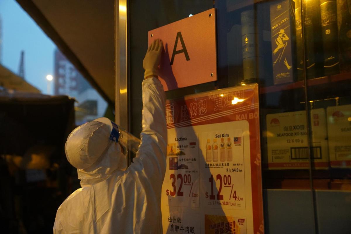油麻地區疫情持續升温，政府首度實施圍封，劃定佐敦一帶指明的「受限區域」，區內約1萬人須禁足至所有受檢人士完成檢測及有結果，預計行動需時兩日完成。自今日（23日）凌晨開始，數批身穿保護衣的入境處人員在疫區內執勤，協助當區的居民，並駐守在各個路口。（入境處供圖）
