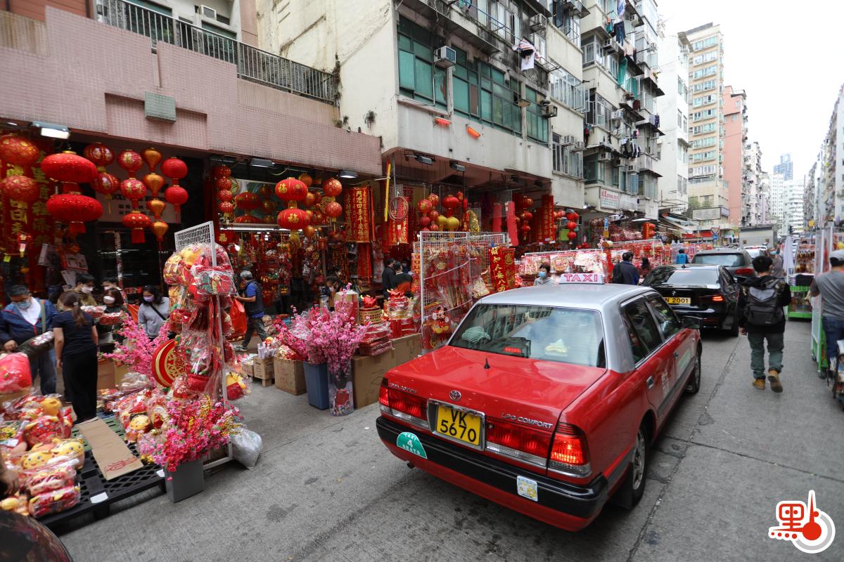 不少店鋪在路邊開檔賣牛年賀年公仔、特色揮春，利是封等，大半條街都一片紅噹噹，充滿濃厚節日氣氛。（點新聞記者李斯哲攝）