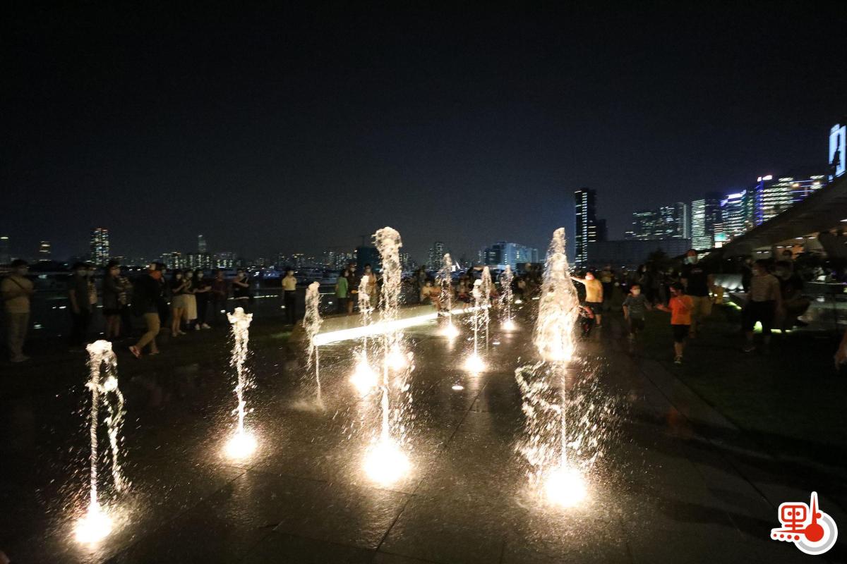入夜後，音樂噴泉在燈光的配合下更顯閃亮璀璨，吸引不少市民駐足。（點新聞記者萬靈霜攝）