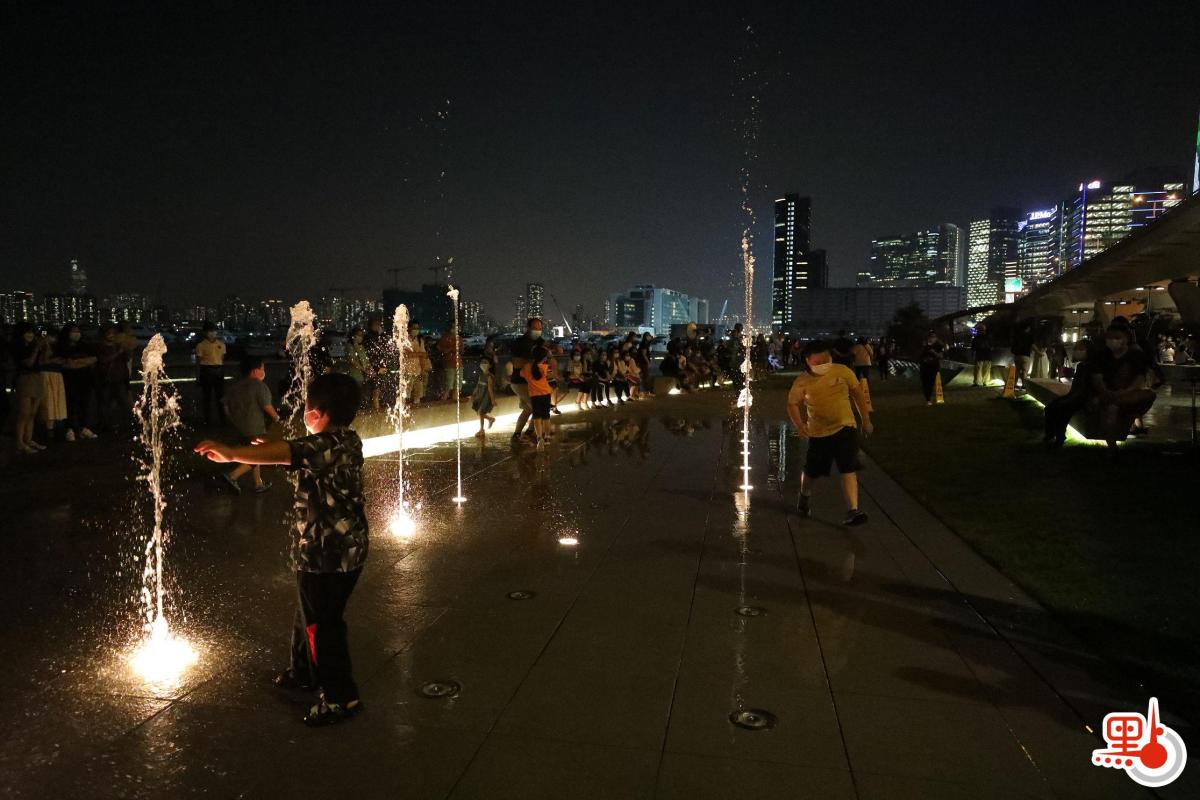 許多小童興奮與噴泉互動，穿梭水柱間嬉戲。（點新聞記者萬靈霜攝）