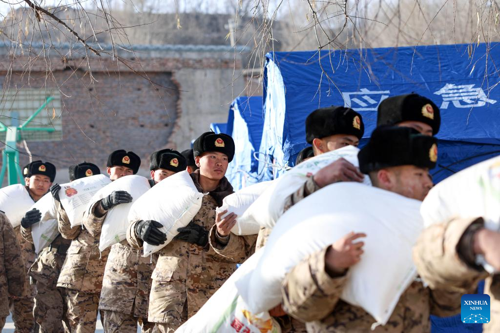 Members of the Chinese People's Armed Police Force help to carry bags of flour for quake-affected people in Liuji Township, Jishishan County, northwest China's Gansu Province, Dec. 21, 2023. The Chinese People's Liberation Army (PLA) and the People's Armed Police Force (PAPF) have deployed multiple rescue forces to quake-hit areas in response to a 6.2-magnitude earthquake that jolted northwest China's Gansu Province late Monday. (Photo by Hou Chonghui/Xinhua)