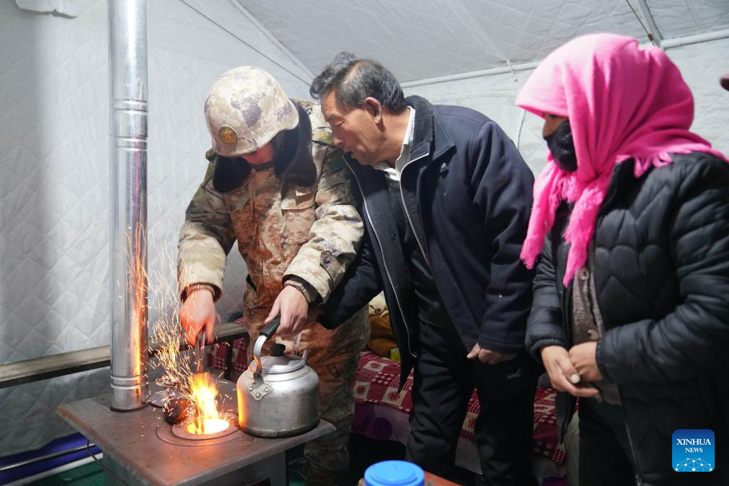 A soldier lights the fire in a stove for quake-affected people in Liugou Township, Jishishan County, northwest China's Gansu Province, Dec. 19, 2023. The Chinese People's Liberation Army (PLA) and the People's Armed Police Force (PAPF) have deployed multiple rescue forces to quake-hit areas in response to a 6.2-magnitude earthquake that jolted northwest China's Gansu Province late Monday. (Xinhua/Zhang Yongjin)